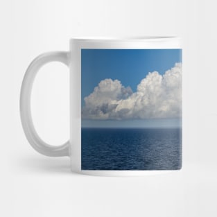 White cumulus clouds in sky over blue Baltic sea Mug